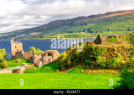 Malerischer Blick auf Urquhart Castle Site mit einer schottischen Flagge und Loch Ness Landschaft mit einem Boot nähert, Schottland Stockfoto