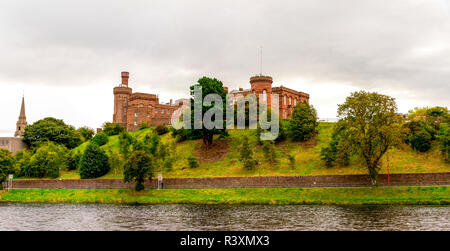 Panorama der Fluss Ness Promenade mit einer malerischen roten Stein Inverness Castle auf einem Hügel, Schottland Stockfoto