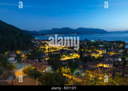 Berühmte Europäische See in der Abenddämmerung. Lago Maggiore mit der Stadt von Maccagno, im Hintergrund die Lichter von Luino, Lombardei, Nord Italien Stockfoto