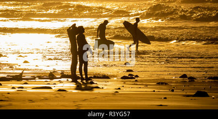 Surfer bei Sonnenuntergang in La Cicer am Strand Las Canteras in Las Palmas, Gran Canaria, Kanarische Inseln, Spanien. Stockfoto