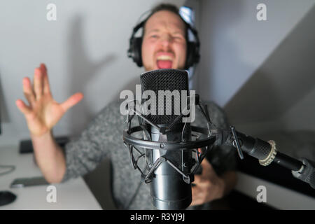 Junge männliche hinter Kondensator Mikrofon radio podcast Host voice recording Stockfoto