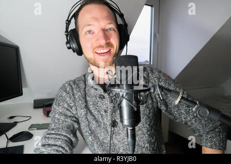 Junge männliche hinter Kondensator Mikrofon radio podcast Host voice recording Stockfoto