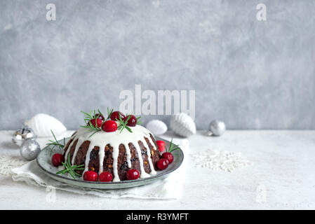 Christmas Pudding, Obst Kuchen mit Puderzucker und Preiselbeeren auf weißen Tisch dekoriert, kopieren. Hausgemachte, traditionelle Weihnachten Dessert - Weihnachten Pudd Stockfoto