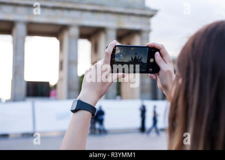 Hände halten Telefon Handy und nimmt Bilder der berühmten historischen Sehenswürdigkeiten. Das Brandenburger Tor neoklassizistisches Denkmal in Berlin. Stockfoto