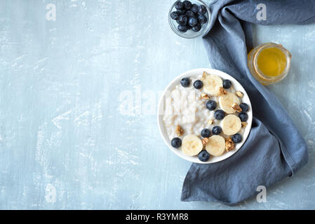 Haferflocken Porridge mit Walnüssen, Blaubeeren und Banane in der Schüssel - gesundes Bio-Frühstück, Hafer mit Früchten, Honig und Nüssen. Stockfoto