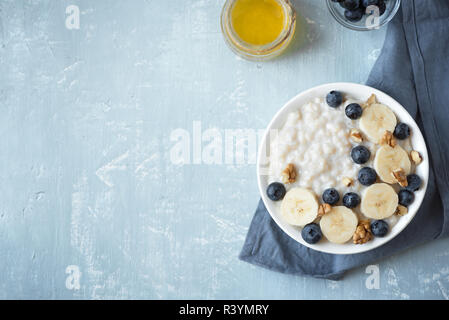 Haferflocken Porridge mit Walnüssen, Blaubeeren und Banane in der Schüssel - gesundes Bio-Frühstück, Hafer mit Früchten, Honig und Nüssen. Stockfoto