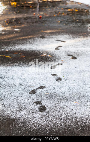 Fußabdrücke in nassen Weg, den ersten Schnee bedeckt Stockfoto