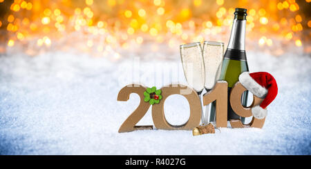 Frohes neues Jahr 2019 Nummer mit weihnachtsmütze Four Leaf Clover Flasche Champagner Glas vor Golden bokeh lghts panorama Schnee Hintergrund Stockfoto