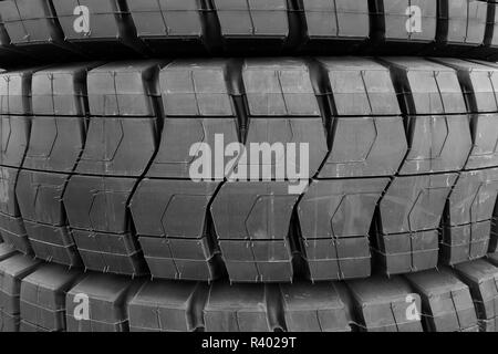 Stapel von riesigen industriellen Größe neue schwarze Gummireifen mit Muster treten. Stockfoto