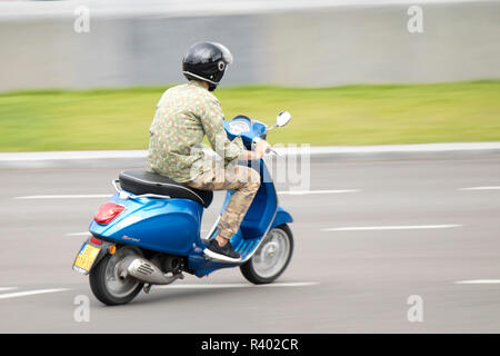 Belgrad, Serbien - Juli 19, 2018: Ein junger Mann in der Tarnung Kleidung reiten schnell blau Roller auf leeren Stadt Straße, Panning Schuß Stockfoto