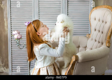 Portrait von Ingwer Haare Mädchen spielen mit Husky poppy. Modell Mädchen mit roten Haaren posiert im Studio Shooting mit Sammy weiße Welpen beim Sitzen auf Royal Retro Stockfoto