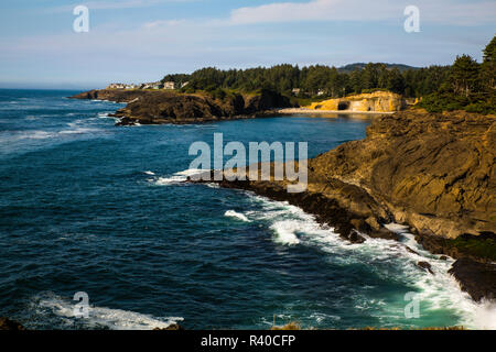 Zerklüftete Küste von Oregon, USA, Pacific Coast Highway 101 Scenic Byway. Eine Höhle und eine kleine Bucht, Häuser, und Wellen Stockfoto