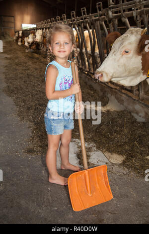 Kleine Mädchen spielen auf dem Bauernhof im Kuhstall Stockfoto