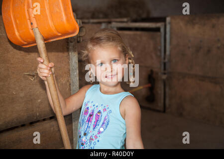 Kleines Mädchen spielt auf dem Bauernhof im Kuhstall Stockfoto