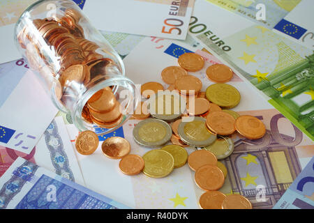 Münzen in der Glasflasche und Euro-banknoten Stockfoto