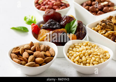 Verschiedene Nüsse in einer Schüssel aus Keramik und getrocknete Früchte auf einem Tisch aus Stein. Das Konzept einer gesunden Nachtisch. Stockfoto