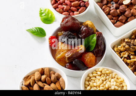 Verschiedene Nüsse in einer Schüssel aus Keramik und getrocknete Früchte auf einem Tisch aus Stein. Das Konzept einer gesunden Nachtisch. Stockfoto