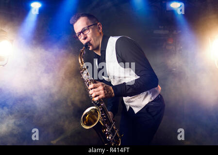 Männliche saxophonist spielen klassische Musik auf Sax. Saxophon Melodie Interpret auf der Bühne in Aktion Stockfoto