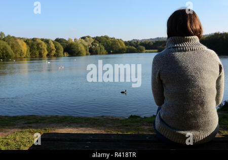 Frau in einem warmen Pullover sitzen nur durch einen See Stockfoto