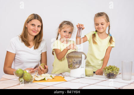Glückliche Familie bereitet frisch gepressten Saft in einen Entsafter Stockfoto