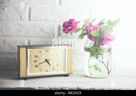 Uhr und rosa Rose auf Stein Wand Hintergrund Stockfoto