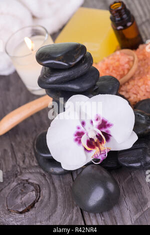 Spa mit ätherischen Öl, Badesalz, Loofah, Steine und Orchidee close-up Stockfoto
