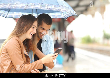 Interracial Paare teilen ein Telefon in einem Bahnhof Stockfoto