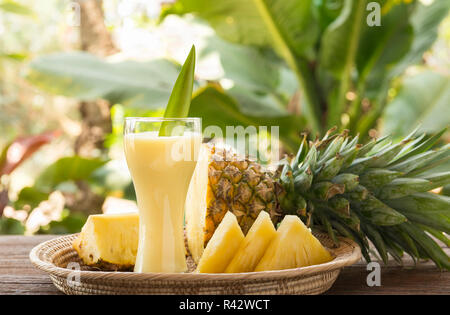 Ananassaft und Ananasscheiben auf einen hölzernen Tisch gelegt. Stockfoto