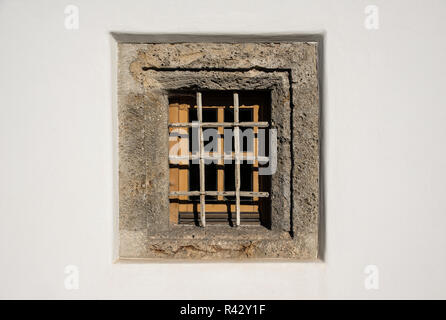 Eine gesperrte Fenster mit Rahmen aus Stein in die strahlend weißen Mauern eines alten Hauses. Stockfoto