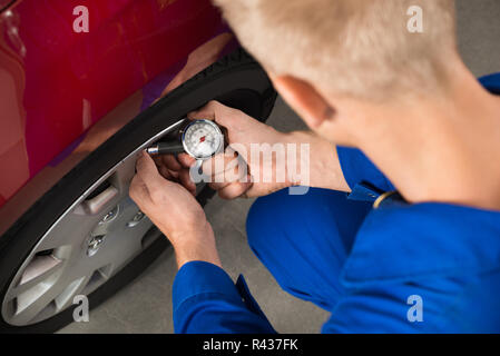 Mechaniker Luftdruck prüfen In Autoreifen Stockfoto