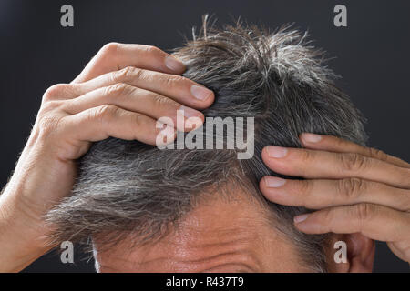 Mann Prüfung sein weißes Haar Stockfoto