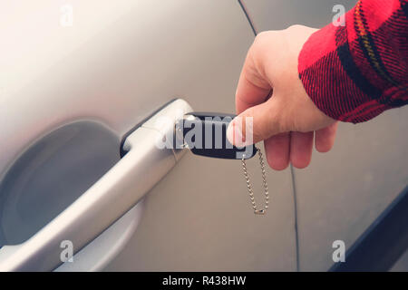 Nahaufnahme der rechten männlichen Hand durch Drehen des Schlüssels in die Öffnung in der Autotür. Man verwendet, um das neue Fahrzeug zu öffnen. Auto Vermietung. Erste Fahrt Stockfoto