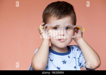 Portrait von niedlichen kleinen Jungen tragen Herz geformte Gläser Stockfoto