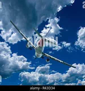 Eine künstlerische skyscape Ansicht eines kommerziellen Passagierflugzeugen fliegen in einem leuchtenden blauen Himmel mit hellen, weißen Cumuluswolken. Stockfoto