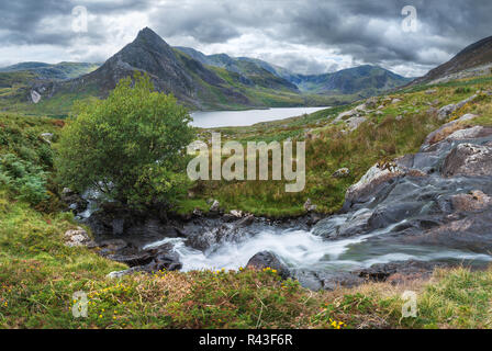 Schöne Panorama Landschaft Bild der Strom fließt über die Felsen in der Nähe von Llyn Ogwen in Snowdonia während eary Herbst mit Tryfan im Hintergrund Stockfoto