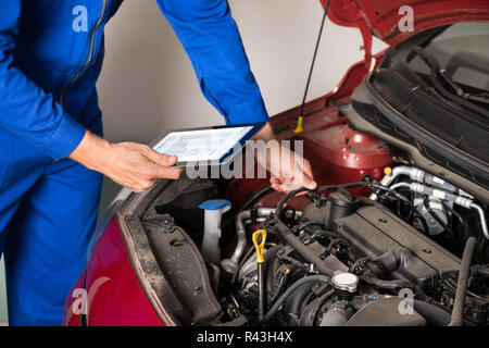 Mechaniker mit digitalen Tablet während der Prüfung Auto Motor Stockfoto