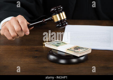 Korrupte Richter schlagen Dollar Bündel auf Hammer am Schreibtisch Stockfoto