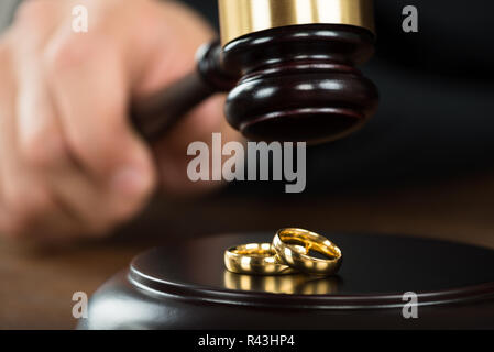 Scheidung Richter schlagen Hammer auf goldenen Ringe am Schreibtisch Stockfoto