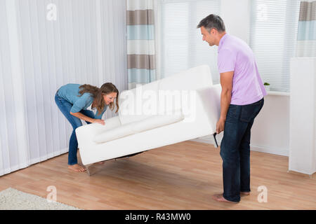 Paare, die versuchen, eine Couch zu bewegen Stockfoto