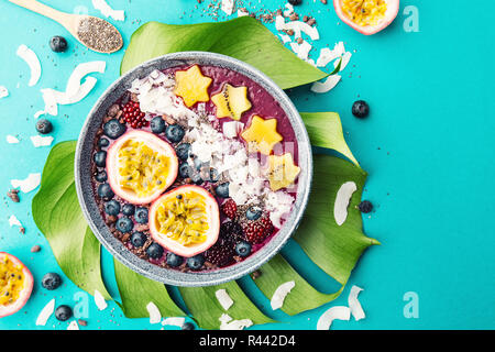 Lecker appetitlichen Smoothie acai Schale von Brombeeren und wilde Beeren, mit Passionsfrucht, Kokosflocken dekoriert, und Kakao Nibs. Serviert Stockfoto