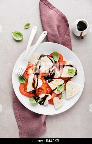 Valentinstag Salat. Klassische italienische Caprese Salat mit Herz gebildet, Mozzarella, Basilikum, Balsamico und Tomaten auf dem Teller serviert. Oben betrachten. Kopieren spa Stockfoto