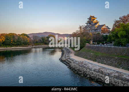 Okayama Castle am Fluss Asahi in Japan in der Abenddämmerung Stockfoto
