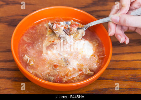 Löffel mit Kohl Suppe in der Hand über Keramik Schüssel Stockfoto