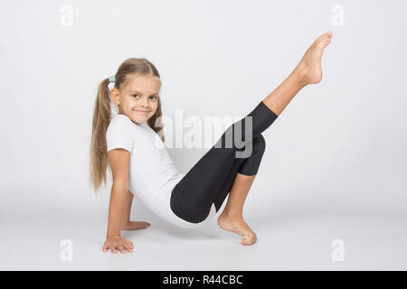 Ein aufstrebender Turnerin zieht sein rechte Bein ruht auf den Händen und Fingern des linken Beines Stockfoto