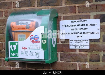 Public Access defibrillator an der Wand der Dorfhalle im East Preston, West Sussex, UK befestigt Stockfoto