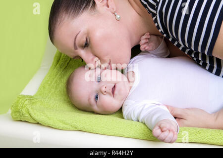 Happy fürsorgliche Mutter mit einem lächelnden Mädchen und küsst sie auf wickelunterlage. Das Konzept der Zärtlichkeit der Mutterschaft und die Werte der Familie. Mutter Stockfoto