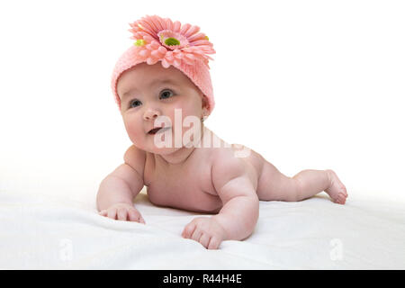 Lustige weiblichen Neugeborenen mit schönen rosa Gestricken Gap auf weißem Hintergrund. Happy Baby Mädchen mit schön gestrickten pinky Cap auf weißem Fell Decke. Neugeborene weari Stockfoto