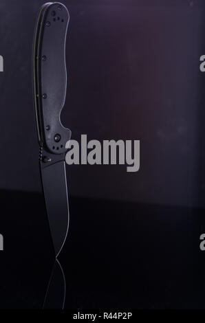 Ein schwarzes Messer und viel Platz. Gegenstand und Luft. Vertikale Rahmen. Stockfoto