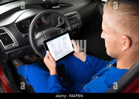 Mechaniker Sitzen im Auto suchen Bei Digital Tablet Stockfoto