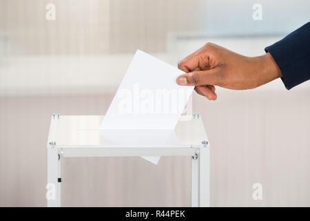 Person's Hand Stimmzettel in Feld Stockfoto